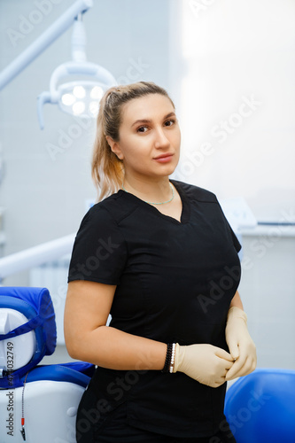 a female dentist in a black uniform at her workplace in the cab of the clinic.