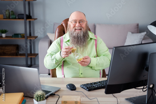 Portrait of attractive cheerful guy top manager working remotely holding sand clock at office indoor work place station photo