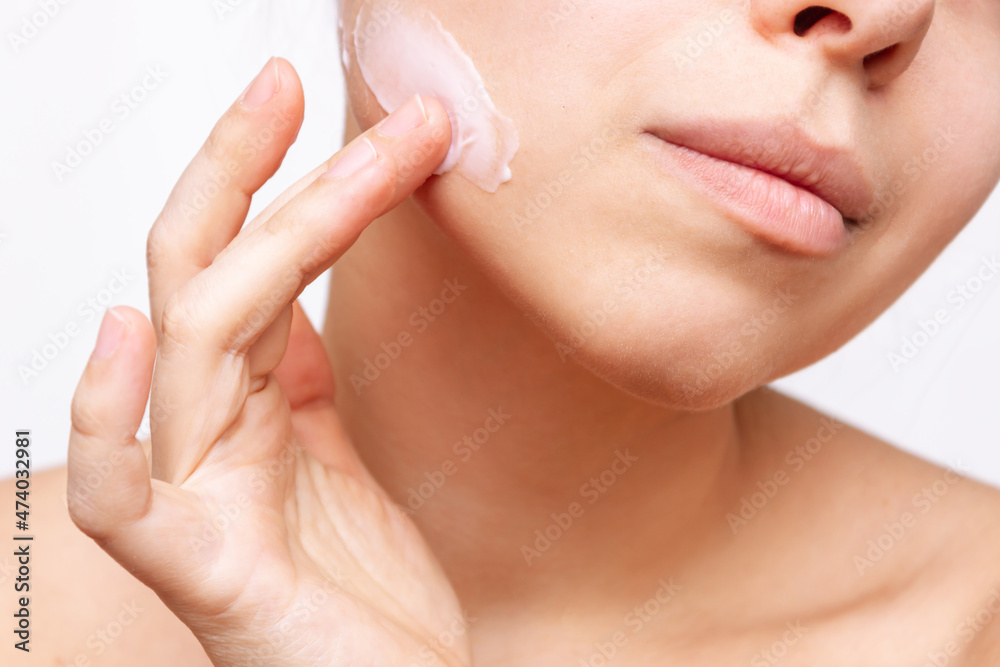Cropped shot of a young caucasian woman touching the face with her hand applying a cream on the skin isolated on a white background. Nourishing moisturizing cream. Cosmetology and beauty concept Cropped shot of a young caucasian woman touching the face with her hand applying a cream on the skin isolated on a white background. Nourishing moisturizing cream. Cosmetology and beauty concept