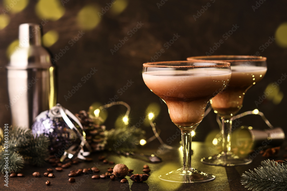 Alexander cocktail in cocktail glass on wooden table with shaker, nutmeg and small grater with Christmas decor on dark background. Beverage photography. Festive cocktail drink. Alexander cocktail in cocktail glass on wooden table with shaker, nutmeg and small grater with Christmas decor on dark background. Beverage photography. Festive cocktail drink.