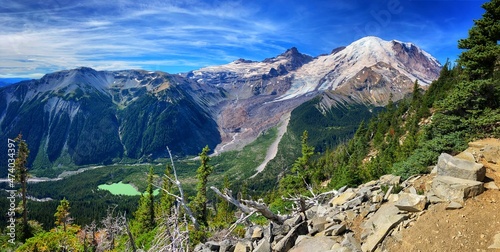 landscape of mount rainier volcano with glaciers, green lake, forest, blue sky