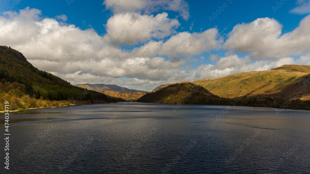 lake, hills and blue sky with fluffy white clouds