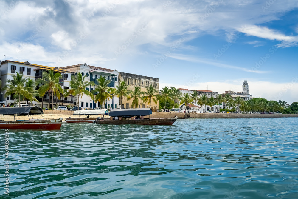 The skyline of Stone Town in Zanzibar seen from the water. sunny day with clouds. travel concept with turquoise indian ocean