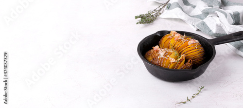 Web banner with Hasselback potato roasted with cheese, bacon and aromatic herbs served in cast iron skillet. Hot meal. Template with copy space on white