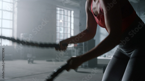 African american sports woman using battle ropes during workout in gym