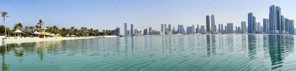 Naklejka premium Panorama beautiful Al Mamzar beach with white sand and palms on ashore of the Arabian Gulf on background modern skyscrapers of Dubai