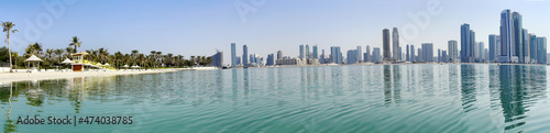 Panorama beautiful Al Mamzar beach with white sand and palms on ashore of the Arabian Gulf on background modern skyscrapers of Dubai © Tanya Keisha