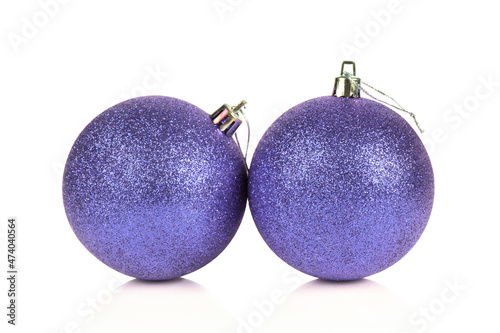 Two glittered Christmas balls colored in color of the year very peri isolated on white background with reflection