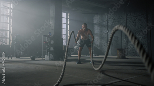 Man practicing exercise with battle ropes. Sportsman doing functional training