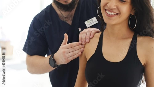 Shoulders massage. Male doctor helps woman woman to recover after trauma in cabinet photo