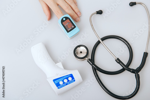 Stethoscope, pulse oximeter and thermometer gun on white background. Phonendoscope. Infrared isometric thermometer gun to check body temperature for virus symptoms. Treatment of cold or flu. photo