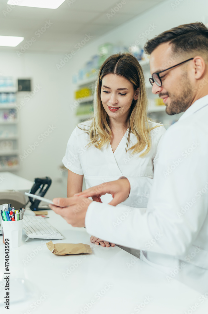 Happy young male and female colleagues pharmacist working in a pharmacy Happy young male and female colleagues pharmacist working in a pharmacy