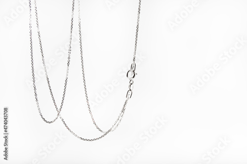 Silver chain hanging on a white background.