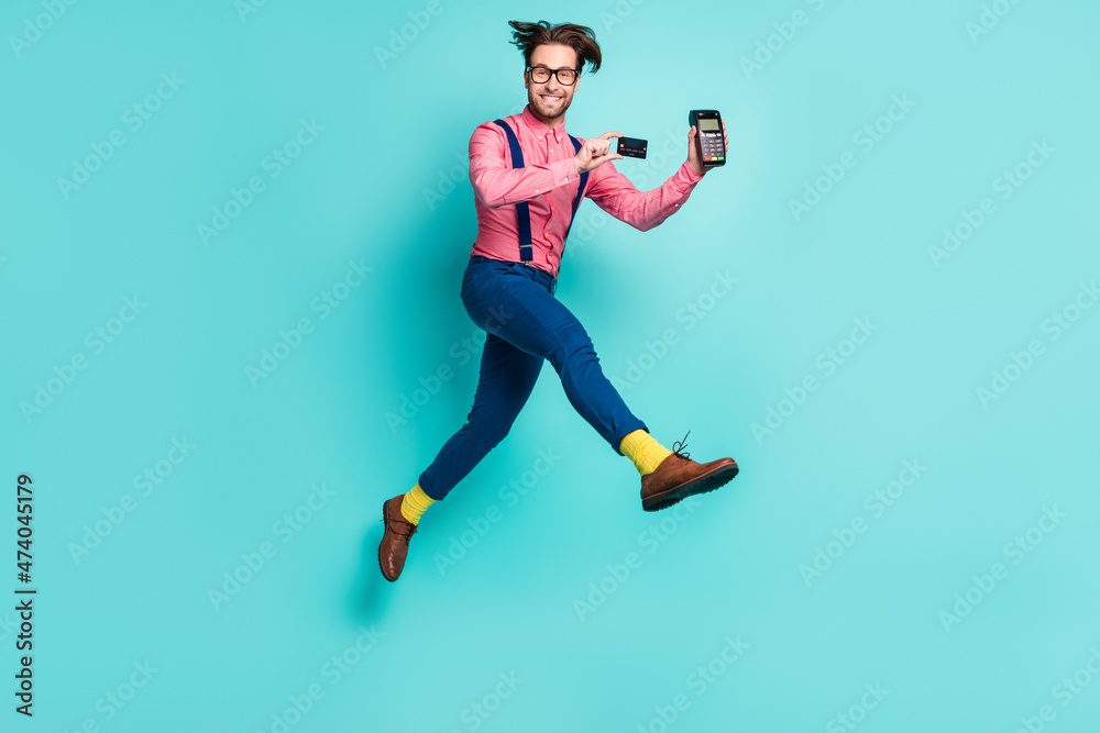 Photo of cute charming gentleman wear pink shirt glasses holding card bank terminal jumping running isolated teal color background