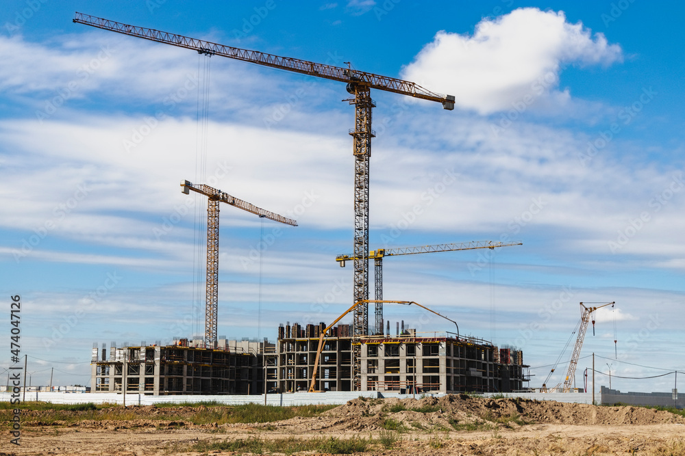 Construction of a monolithic house made of reinforced concrete against the background of a cloudy sky. Tower cranes. Construction technologies. Construction of a modern multi-storey building. Construction of a monolithic house made of reinforced concrete against the background of a cloudy sky. Tower cranes. Construction technologies. Construction of a modern multi-storey building.