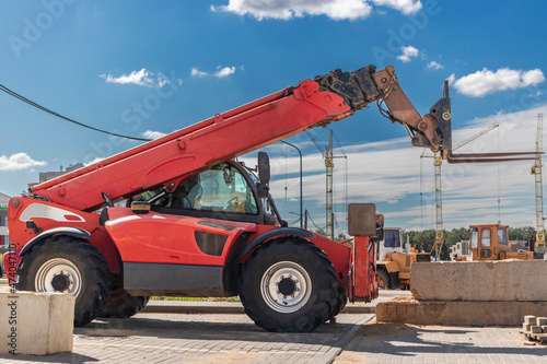 Powerful wheel forklift with telescopic mast at the construction site of a modern residential area. Construction equipment for lifting and moving loads. photo