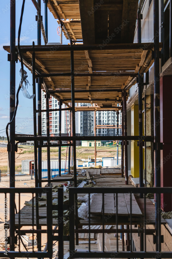 Scaffolding and scaffolding with wooden decks, against a blue sky. Performing construction work at height. Construction safety. Scaffolding and scaffolding with wooden decks, against a blue sky. Performing construction work at height. Construction safety.