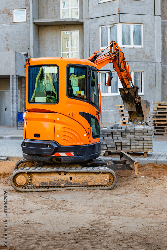 Mini excavator at the construction site. Compact construction equipment for earthworks.