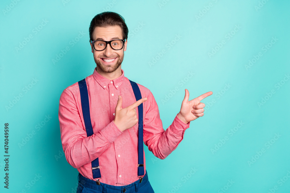 Photo of cheerful amazed young happy man point finger empty space smile isolated on teal color background Photo of cheerful amazed young happy man point finger empty space smile isolated on teal color background