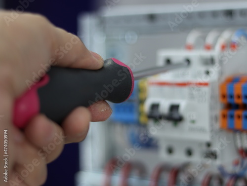 Installation of an electric wire to an automatic current switch using a screwdriver.