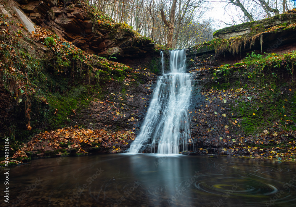 Fototapeta premium Tranquil waterfall scenery in the middle of autumn forest