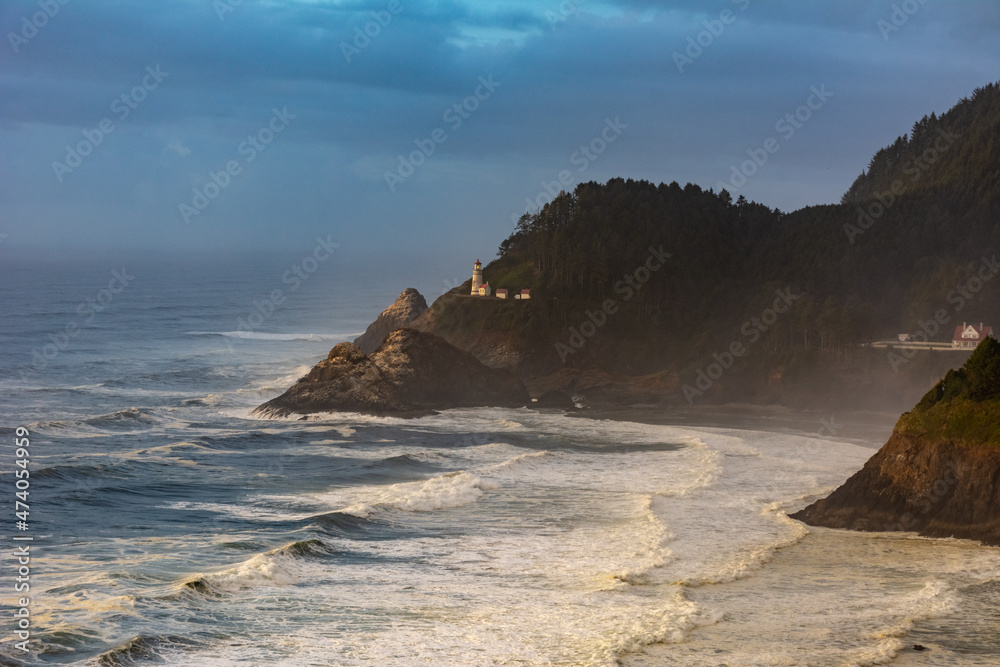 Heceta Head Lighthouse on Oregon coast at night with the Pacific Ocean waves crashing and stormy sky.