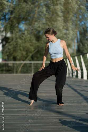 The girl dances beautifully on the embankment of the lake