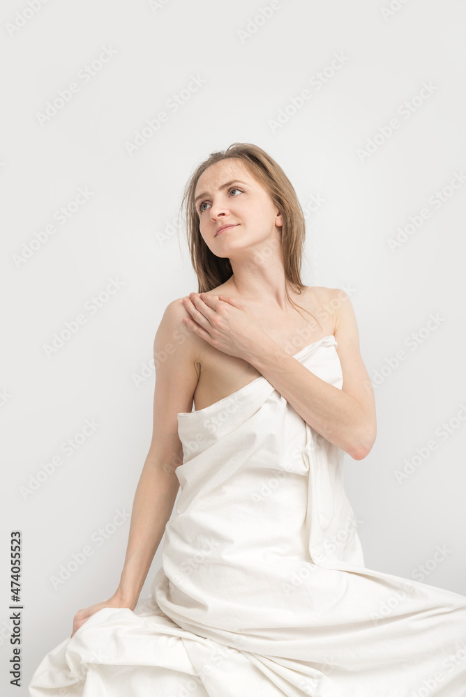 Seductive young woman dressed in sheet on white background. Portrait of naked caucasian girl, covered with sheet. Seductive young woman dressed in sheet on white background. Portrait of naked caucasian girl, covered with sheet.