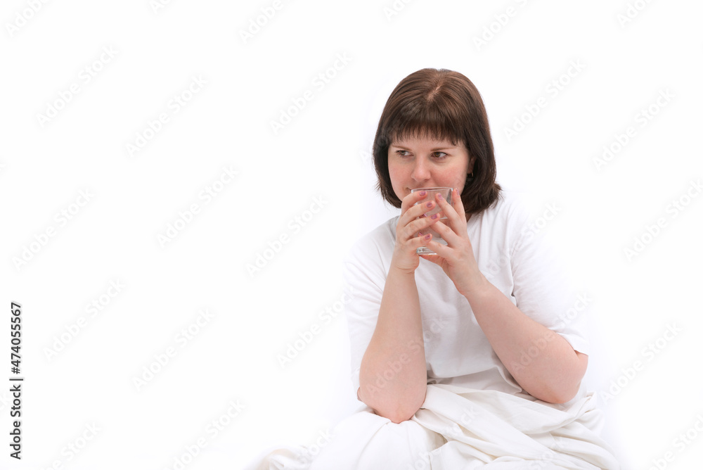 Portrait of young caucasian woman in bed with glass of water. Habit of drinking water in the morning. Copy space. White background Portrait of young caucasian woman in bed with glass of water. Habit of drinking water in the morning. Copy space. White background