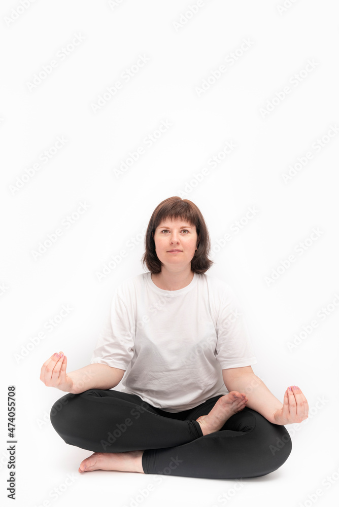 Portrait of caucasian plus size woman on white background practicing yoga. Ardha-padmasana, half lotus pose. Vertical framer. Copy space Portrait of caucasian plus size woman on white background practicing yoga. Ardha-padmasana, half lotus pose. Vertical framer. Copy space