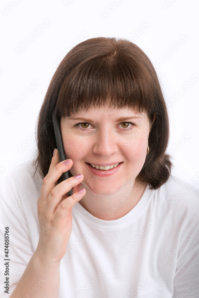 Portrait of young smiling woman with dark hair with phone in her hands. Girl is talking on the phone. Close up. Portrait of young smiling woman with dark hair with phone in her hands. Girl is talking on the phone. Close up.