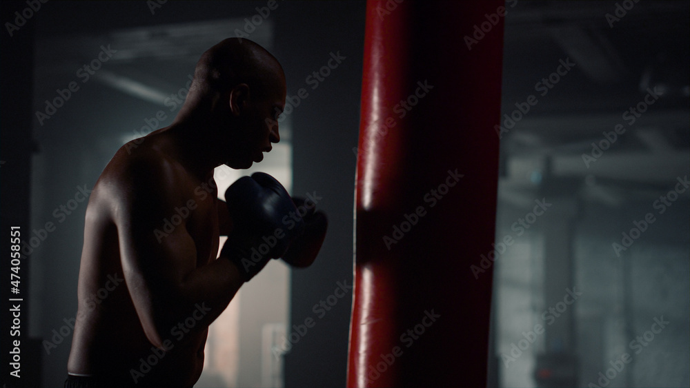 Male kickboxer fighting with punch bag. Guy preparing for fight competition