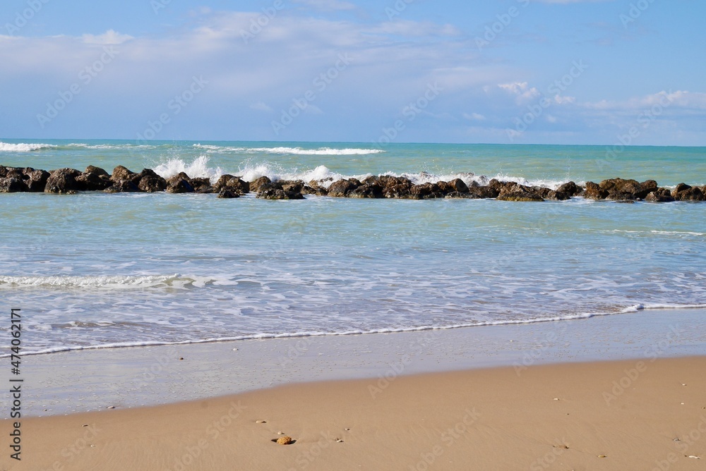 Sandy beach with wave breakers and blue sky. Room for copy space. Sciacca, Sicily, Italy. Sandy beach with wave breakers and blue sky. Room for copy space. Sciacca, Sicily, Italy.