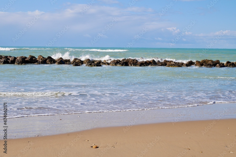 Sandy beach with wave breakers and blue sky. Room for copy space. Sciacca, Sicily, Italy.