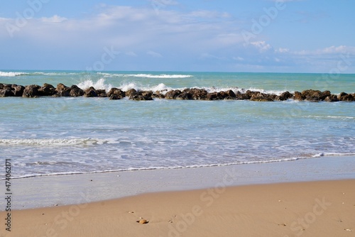 Sandy beach with wave breakers and blue sky. Room for copy space. Sciacca, Sicily, Italy.