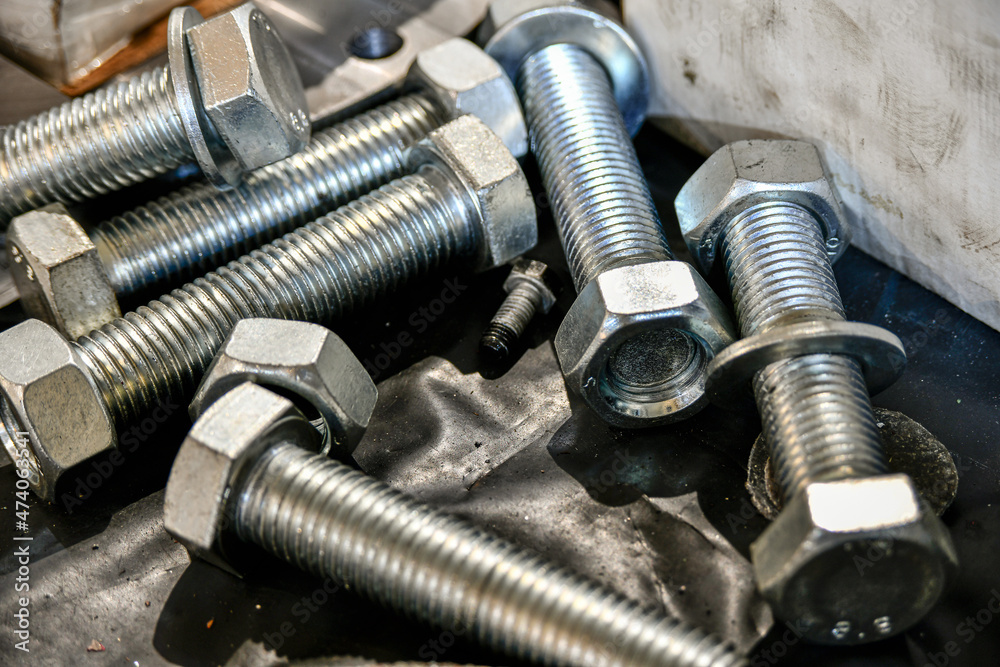 Nuts screwed onto bolts are in a warehouse in a locksmith's shop. Nuts screwed onto bolts are in a warehouse in a locksmith's shop.