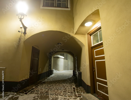 An old medieval passage tunnel in a house and a wooden door with a vintage street light lamp