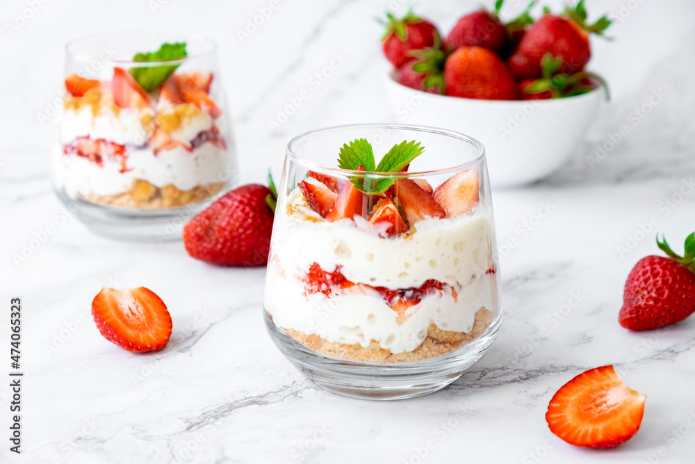 Berry dessert in glass with fresh strawberry, biscuit and whipped cream. Vegan lactose free dessert with alternative milk of coconut. Recipe of healthy organic dessert, cheesecake or berry trifle cake