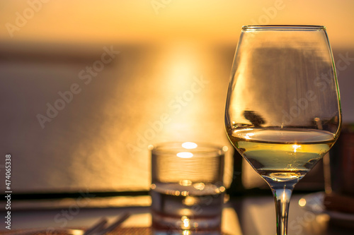 Foto Glass of white wine against sunset with sea in background