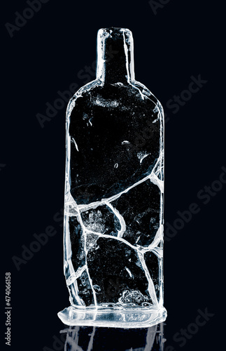 Photography Ice sculpture in form of a glass bottle, made of cracked pure ice on black reflective surface