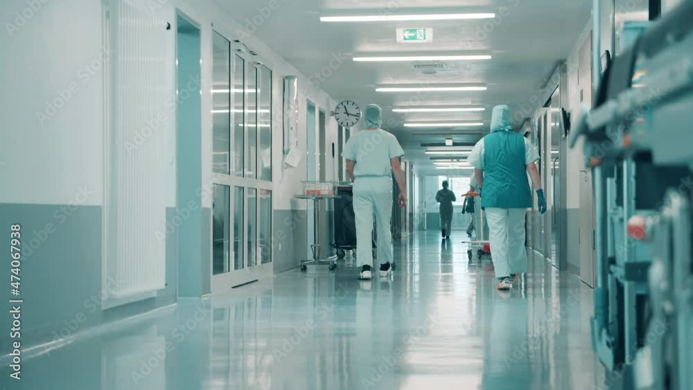 Clinic hallway with medical personnel walking through it Clinic hallway with medical personnel walking through it