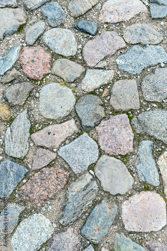 a fragment of a cobblestone pavement of different sizes and shapes. Close-up. Weathered surface