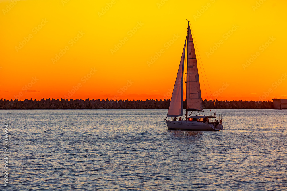 Sochi, Russia, April 13, 2021. View of the sea at sunset time. Sailboat on the horizon
