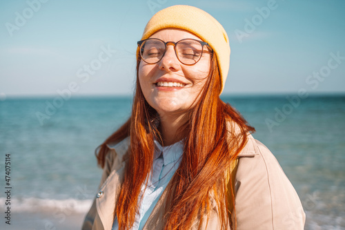 Image of attractive Caucasian young redhead woman smiling enjoying travel and nature sea at sun day photo