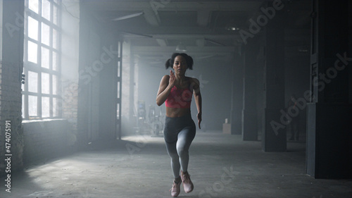 Woman running fast in crossfit gym. Female athlete jogging in sport club