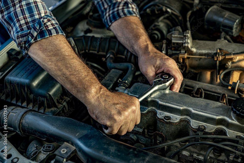 Repairman's male hands with a wrench. Vehicle fitter inspecting used car engine