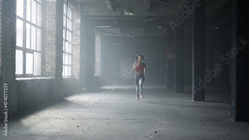 Sportswoman training in loft building. Female jogger running in gym