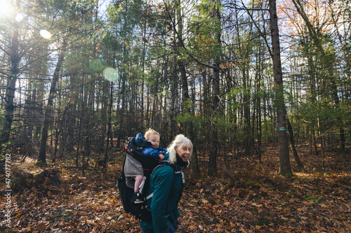 Senior woman carries her granddaughter in a hiking backpack