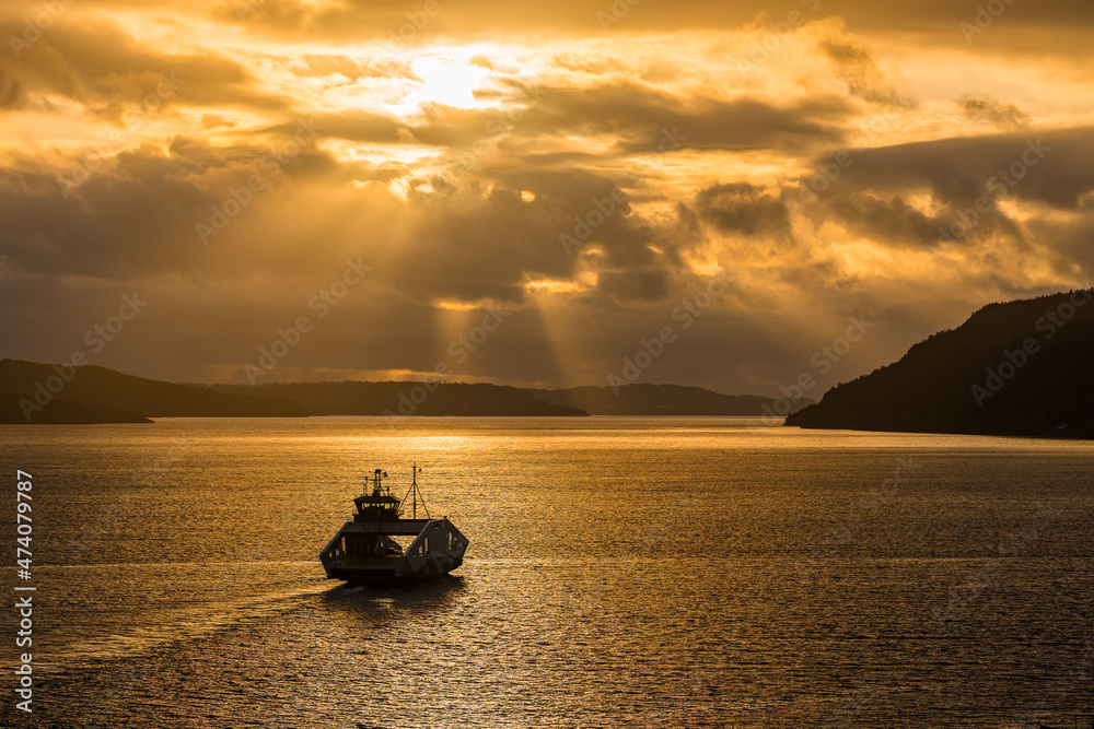 Norwegian ferry operator Norled has the world’s first liquid hydrogen-powered ferry MF Hydra. Beautiful silhouette of car ferry with crazy sunset. Eco-friendly boat. Nesvik ferjekai.