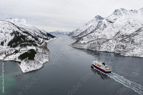Aerial view of fjord in cold winter weather with Hurtigruten ferry turist boat on the sea. Lofoten near Trollfjorden. Panoramatic photography in foggy weather. photo